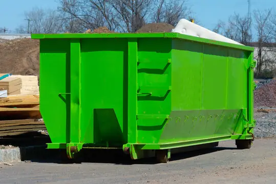 Roll-off dumpster on a construction site with lumber