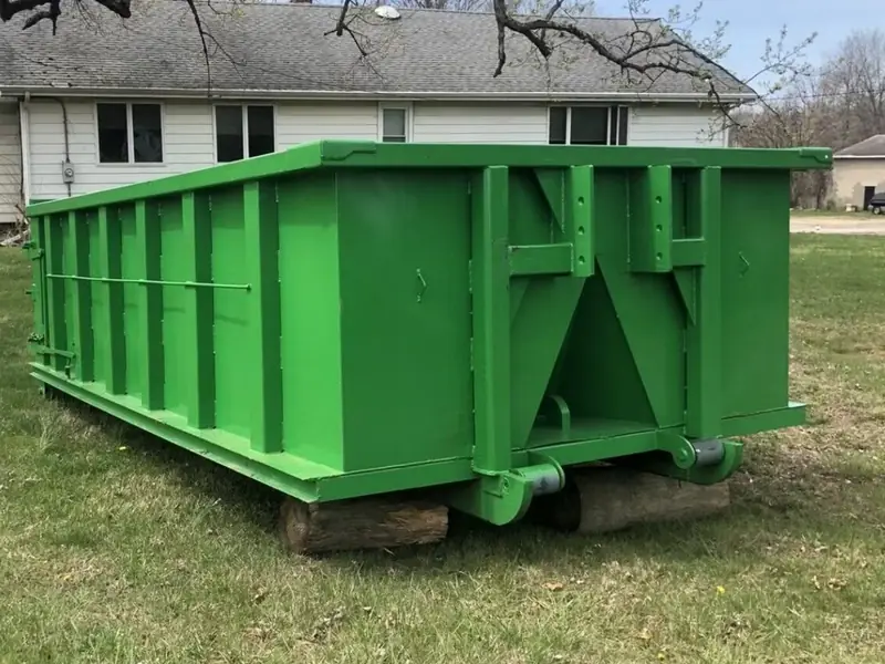 Roll-off dumpster resting on wood beams beside a house